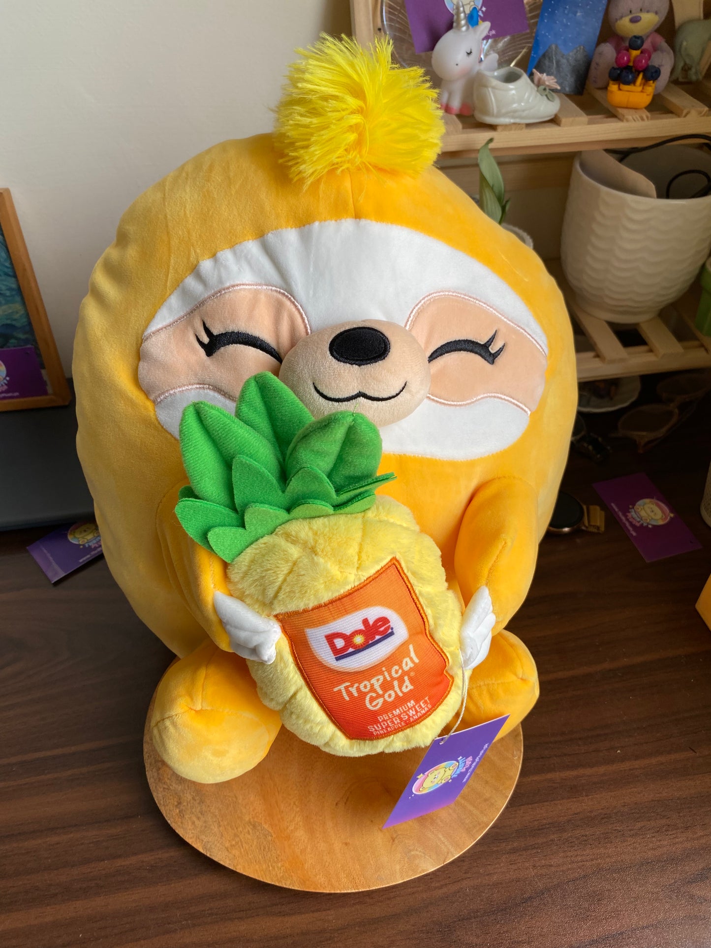 ZURU Snackles plush toy, specifically Sandy the Sloth holding a Dole Tropical Gold Pineapple