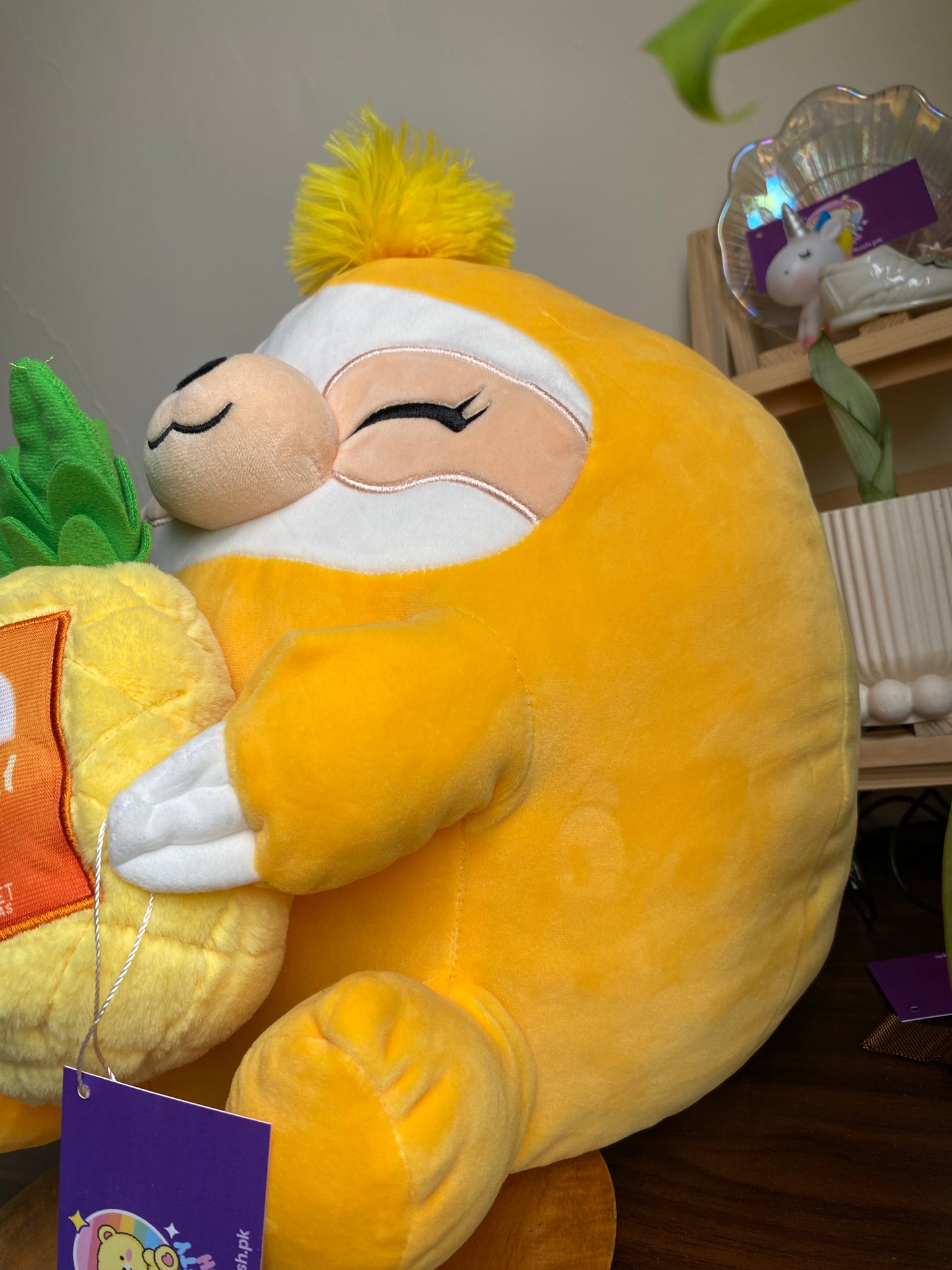 ZURU Snackles plush toy, specifically Sandy the Sloth holding a Dole Tropical Gold Pineapple
