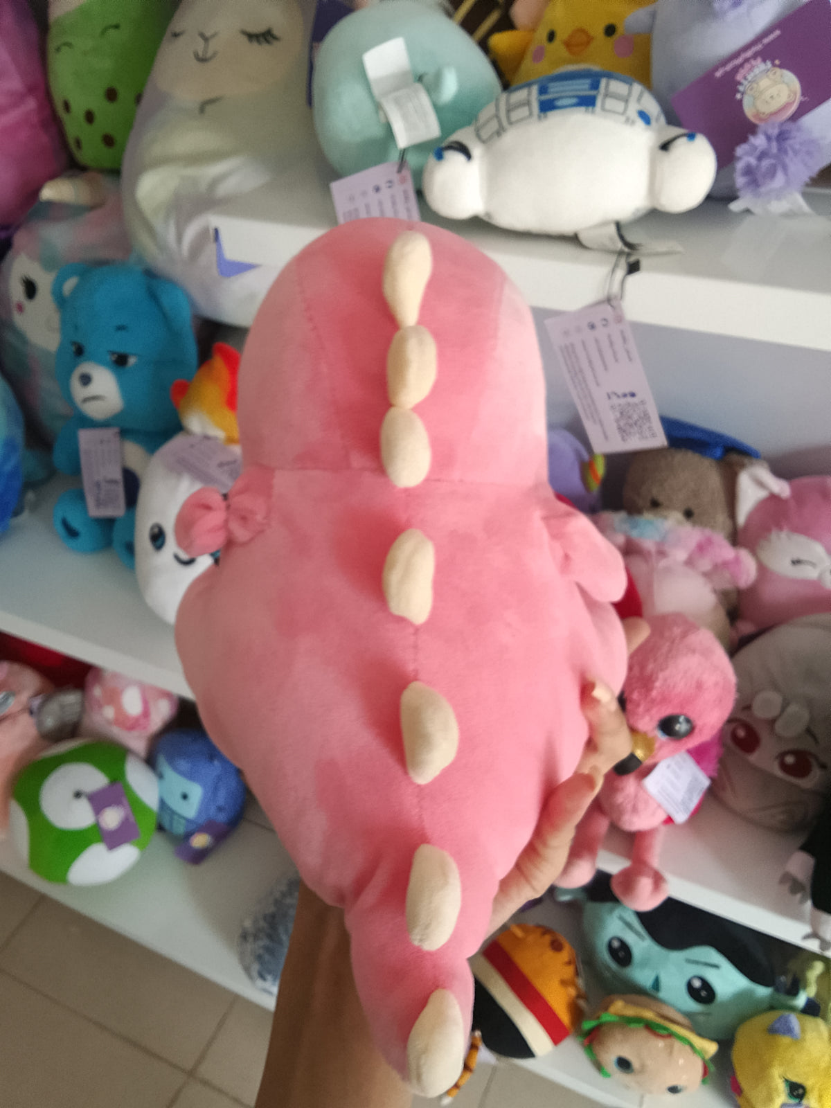 Yobush pink plush dinosaur toy holding a hear.