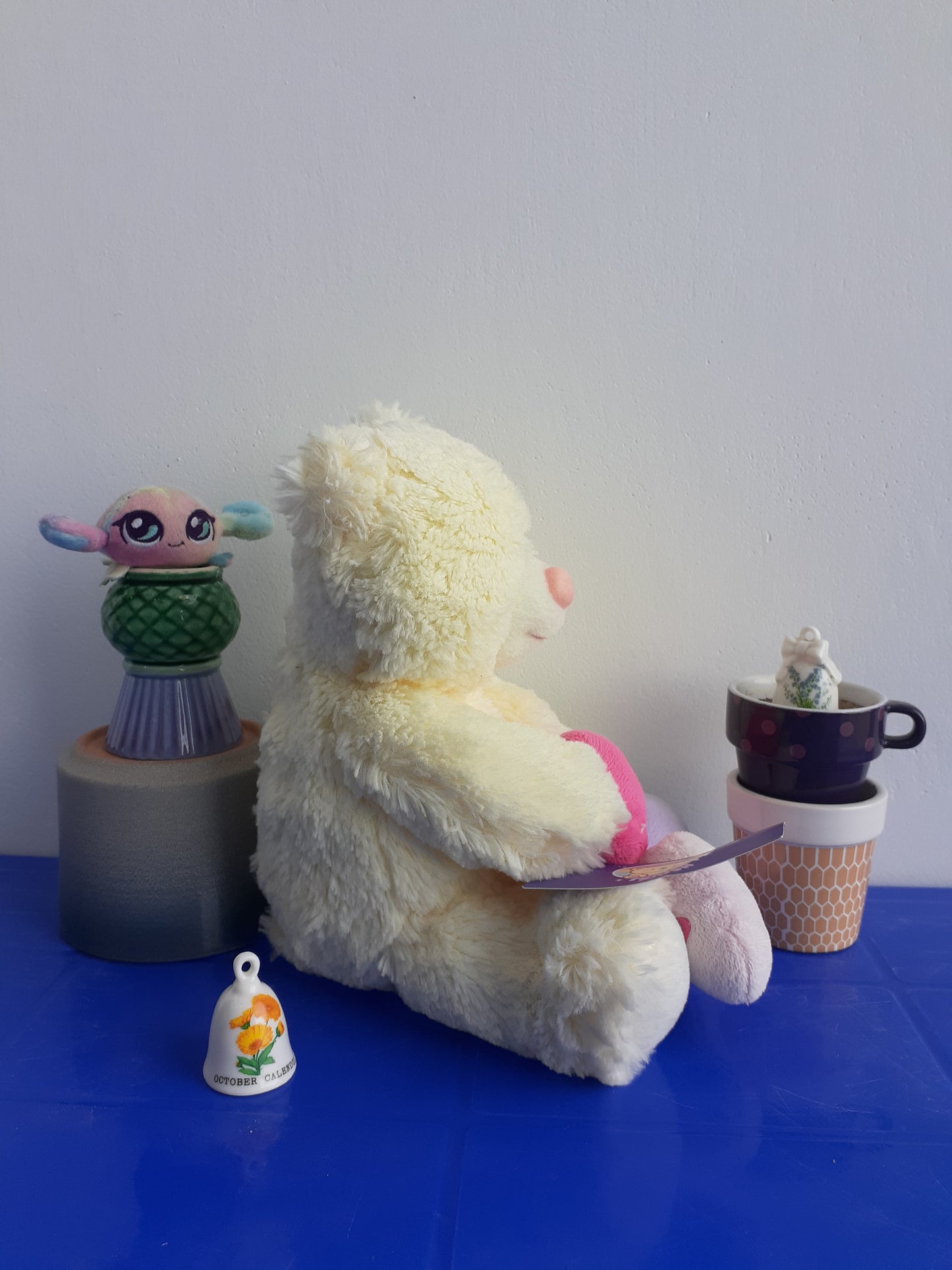 white Teddy Bear with A Pink Nose And Several Small, Colorful Plushie