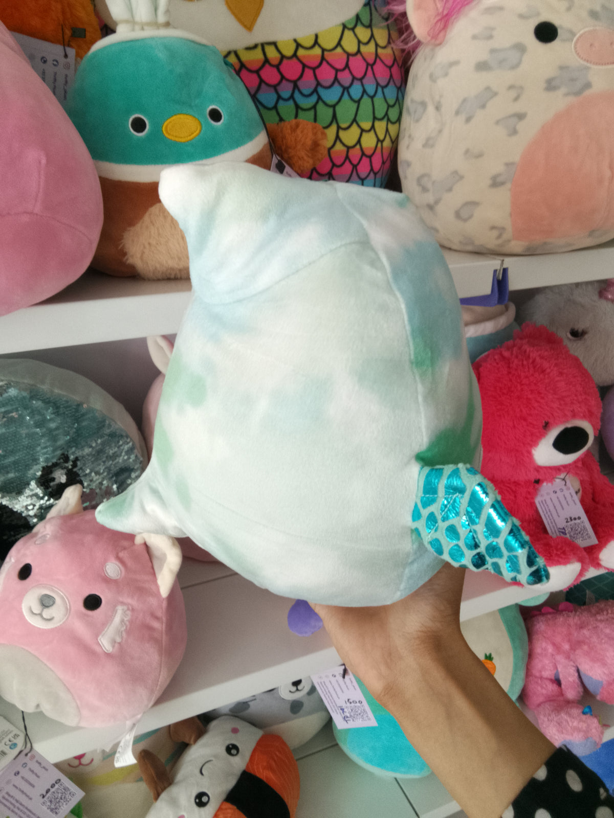 Squishmallows Shantira the Pterodactyl plush toy blue and white tie-dye design and holding a hot chocolate cup.