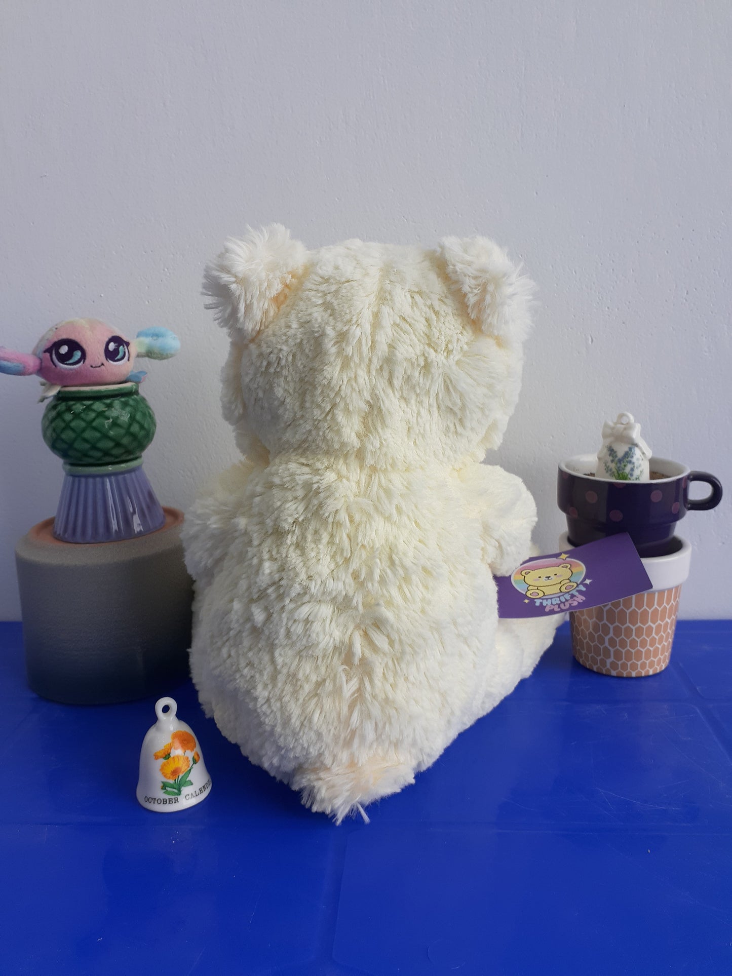 white Teddy Bear with A Pink Nose And Several Small, Colorful Plushie