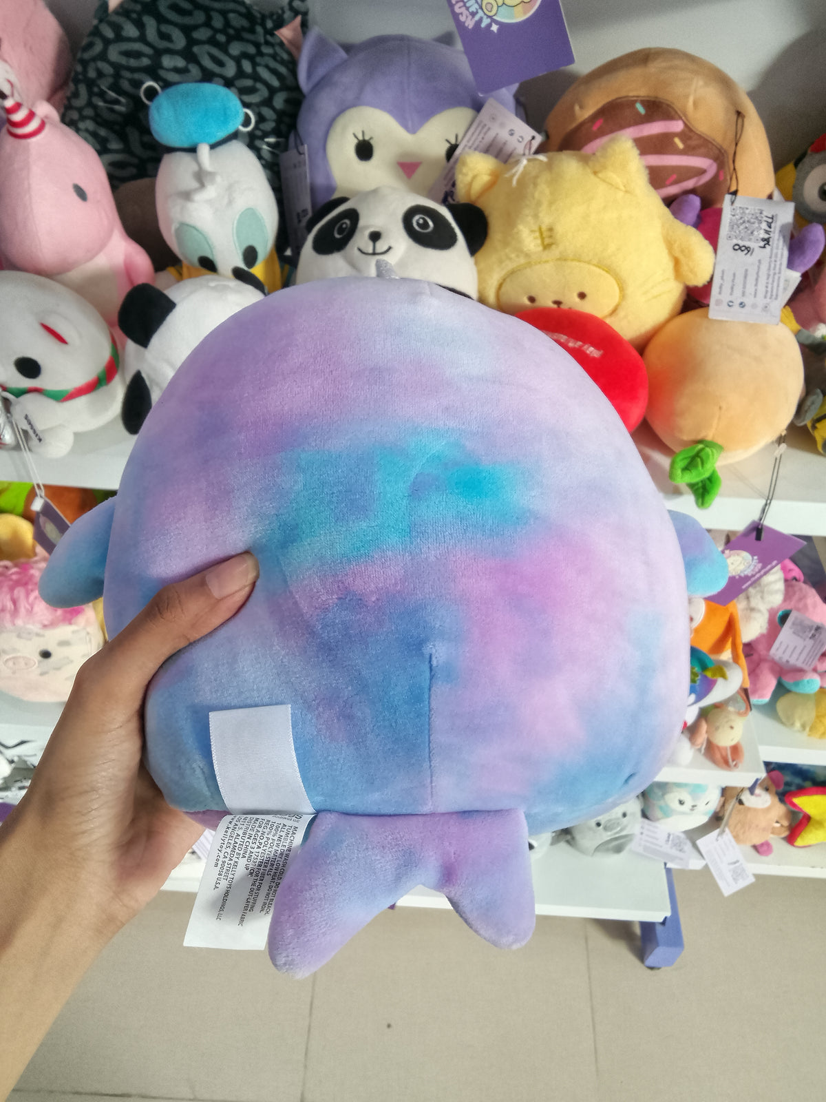Squishmallows Hallie the Tie-Dye Narwhal plush in blue and purple.