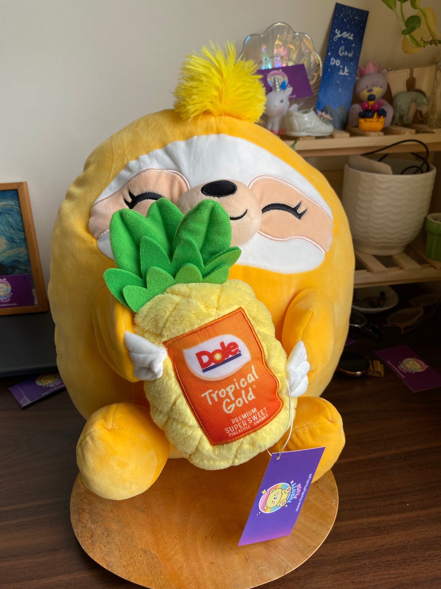 ZURU Snackles plush toy, specifically Sandy the Sloth holding a Dole Tropical Gold Pineapple