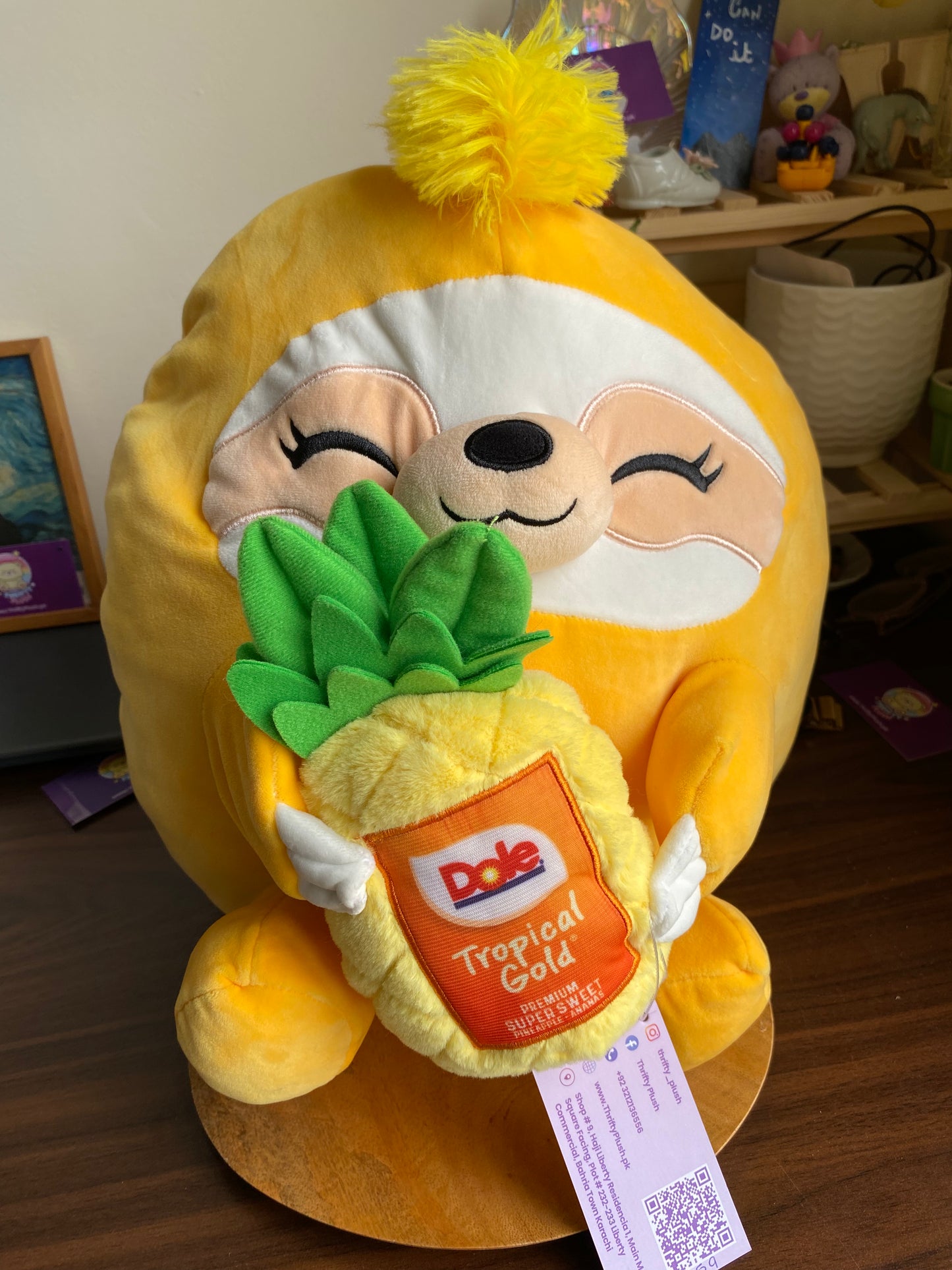 ZURU Snackles plush toy, specifically Sandy the Sloth holding a Dole Tropical Gold Pineapple