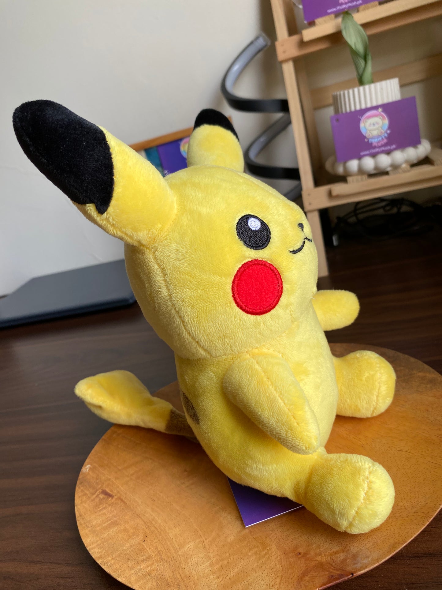 Front view of Pikachu plush, yellow with black-tipped ears and red cheeks
