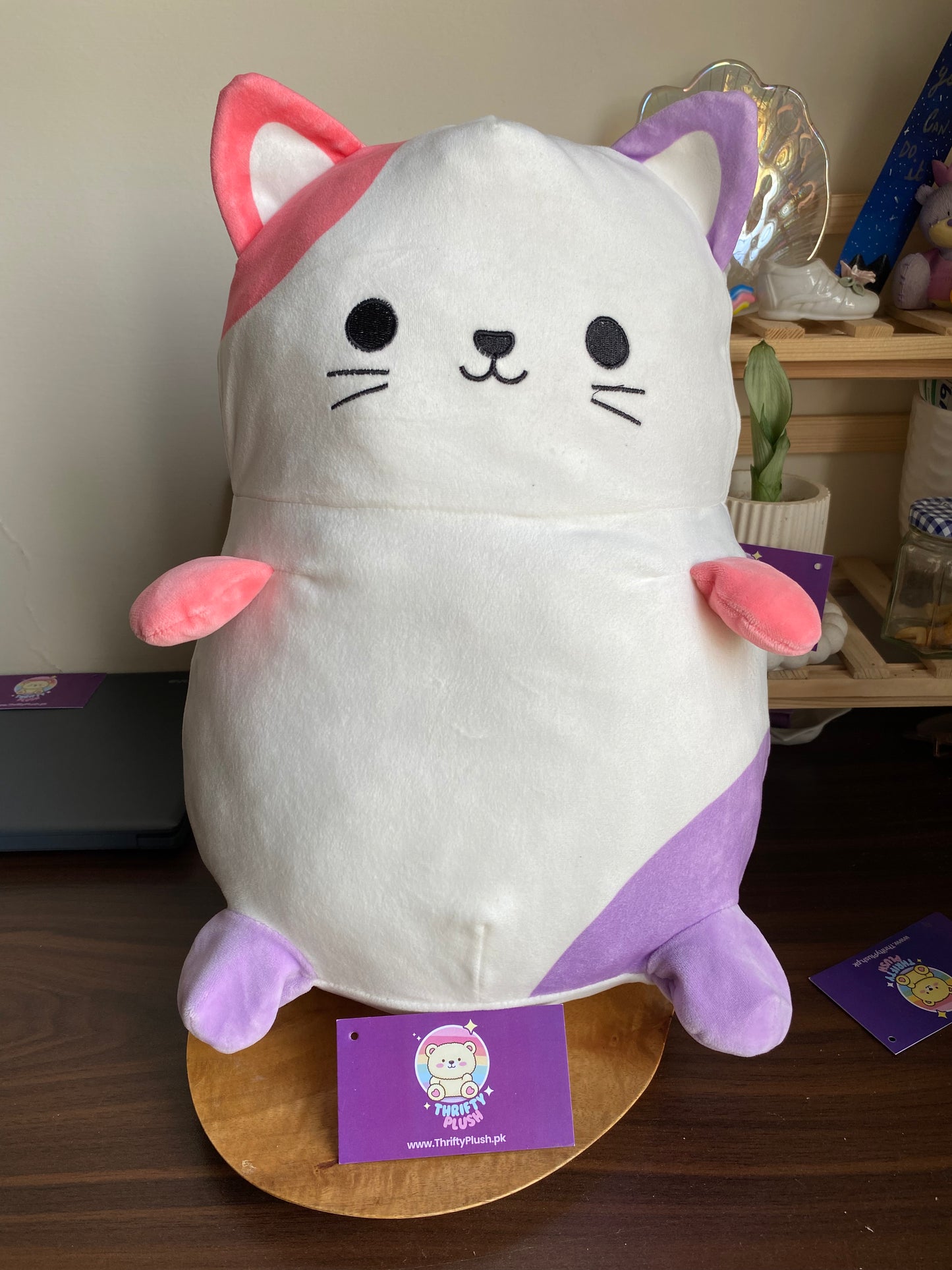 Large kawaii cat plush toy with pink and purple pastel ears and paws from Thrifty Plush