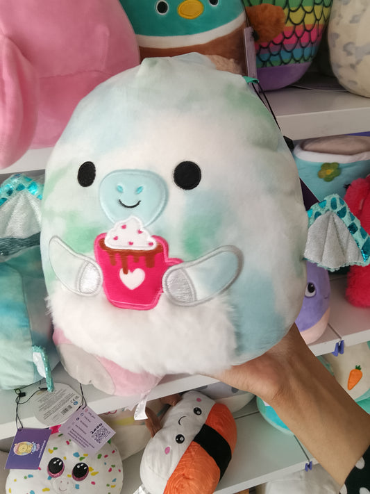 Squishmallows Shantira the Pterodactyl plush toy blue and white tie-dye design and holding a hot chocolate cup.