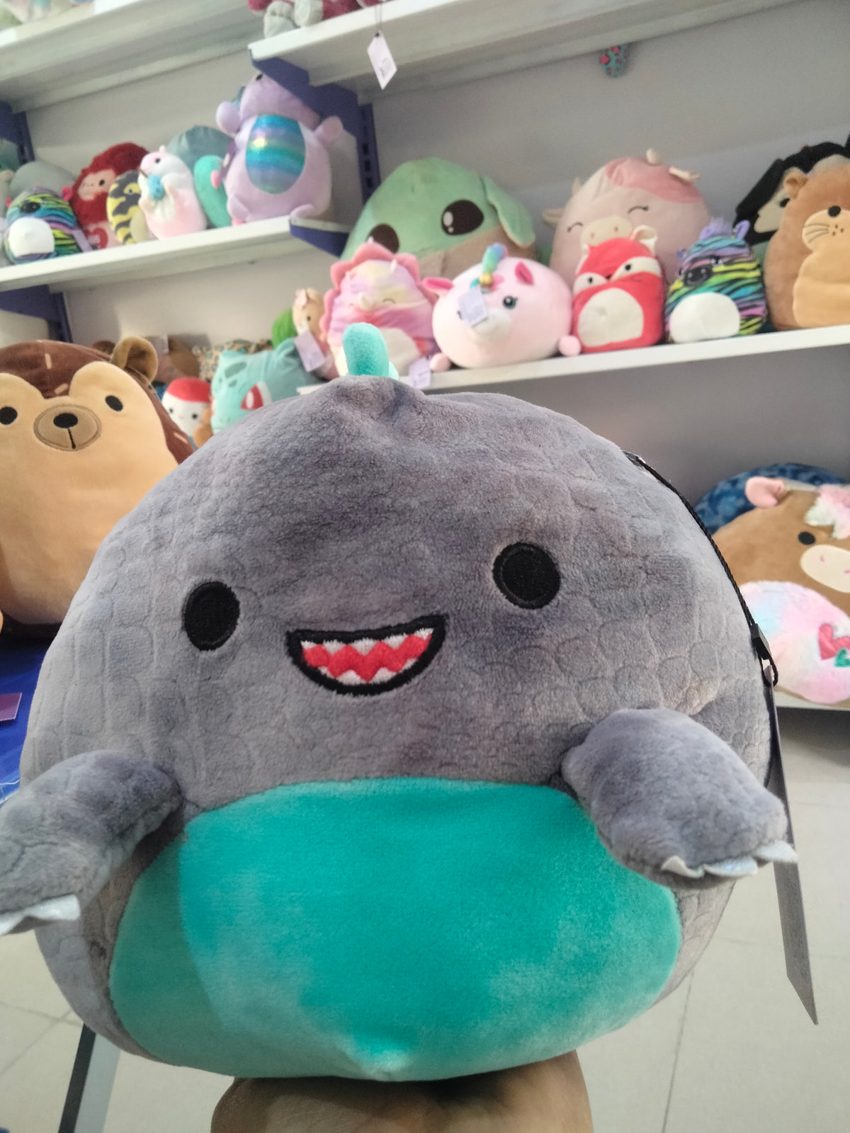 Squishmallows Chuey the T-Rex dinosaur plush in gray and teal.