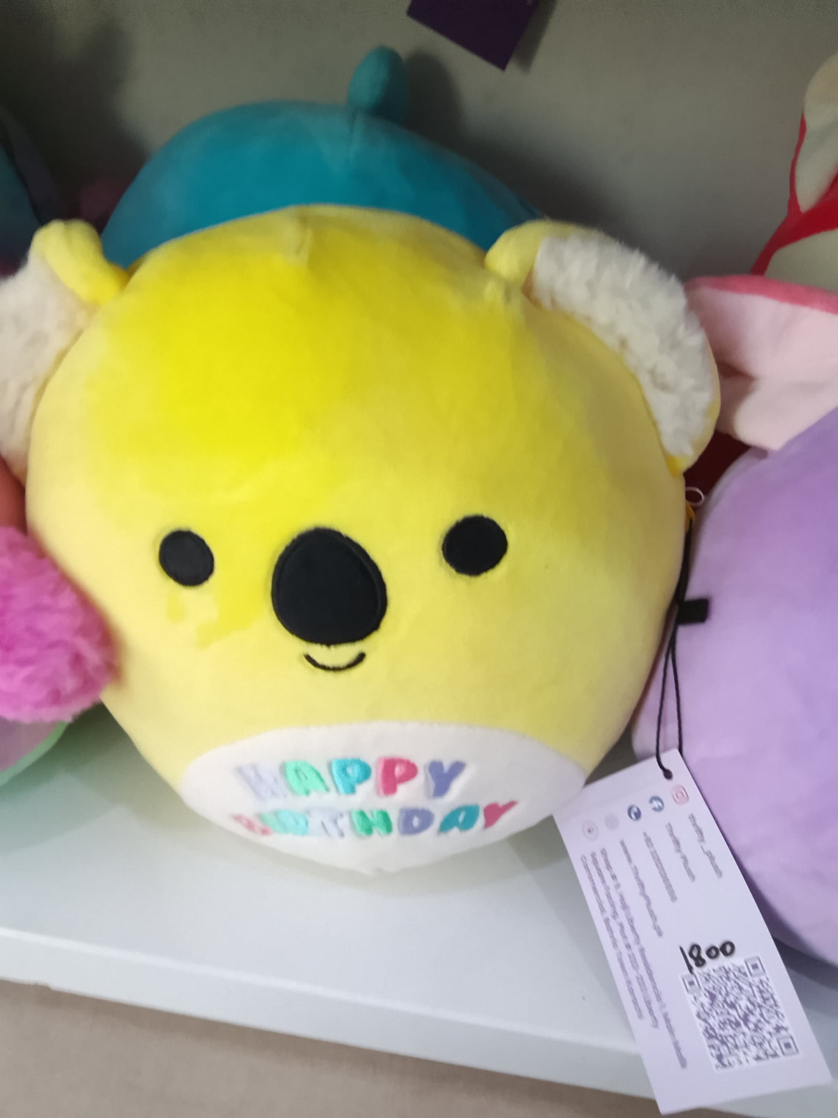 Squishmallows Donny the Koala from the Celebration Squad,yellow plush material and "Happy Birthday" text on the belly.