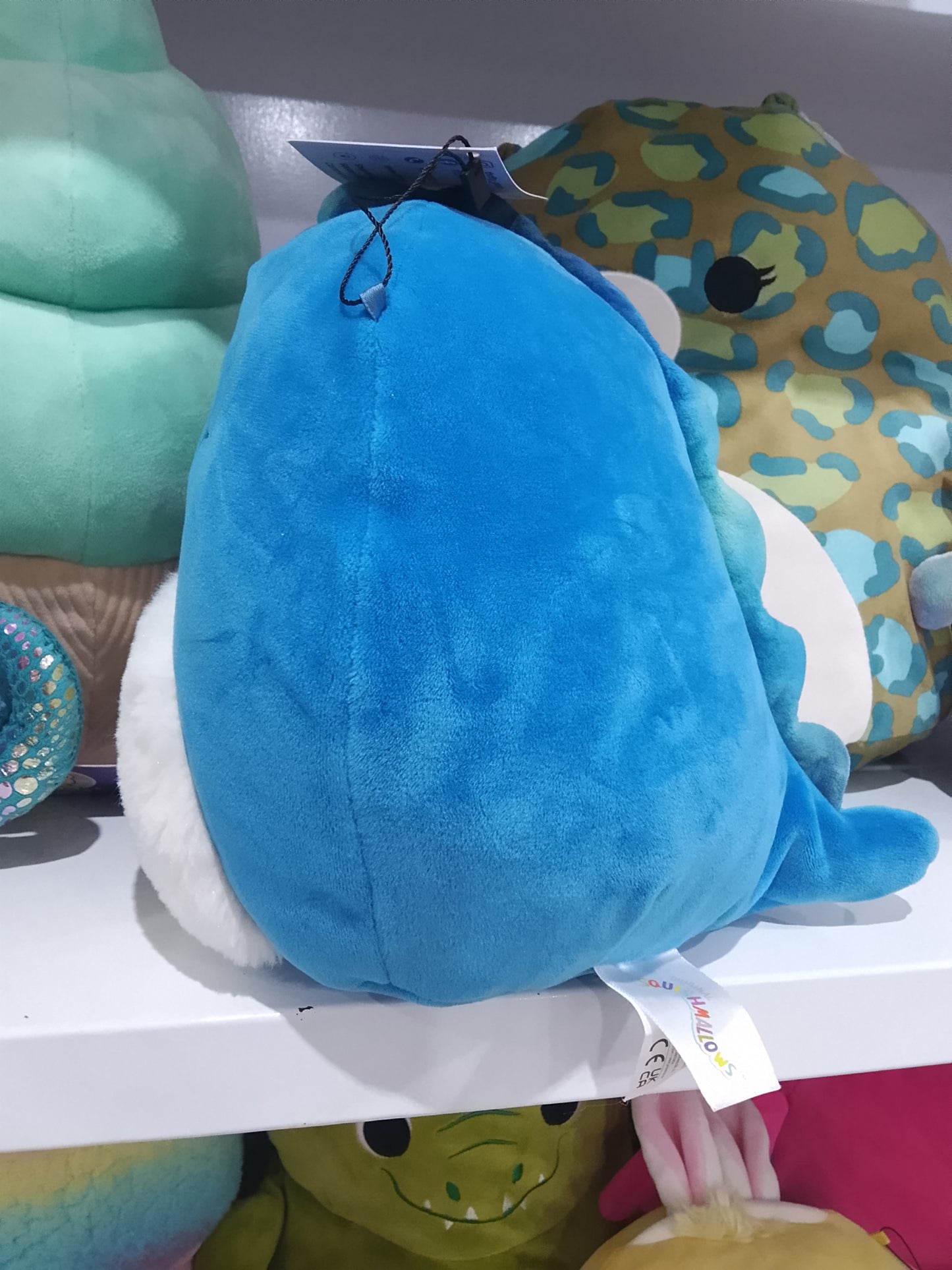 Squishmallows Brody, a blue winking dinosaur with a fuzzy white belly plush toy