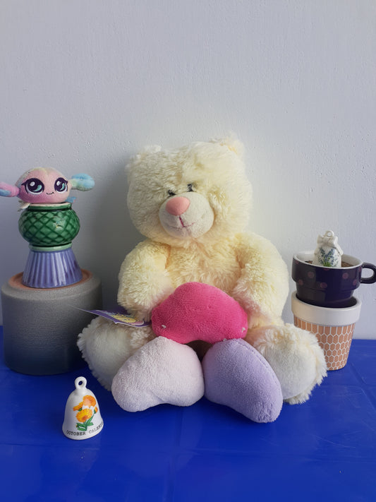 white Teddy Bear with A Pink Nose And Several Small, Colorful Plushie
