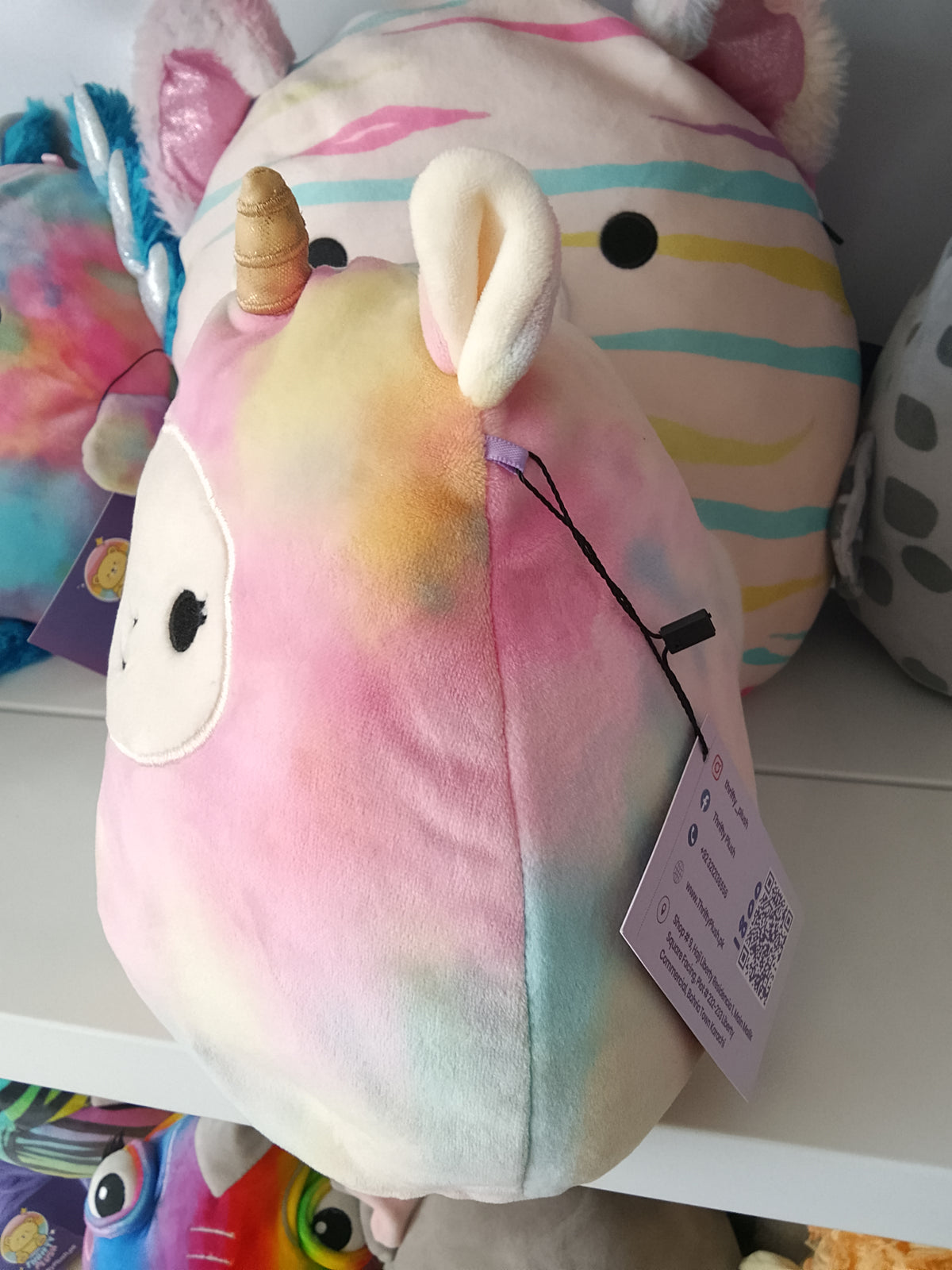 Squishmallows Lucinda the Llamacorn plush toy, featuring a rainbow tie-dye design.