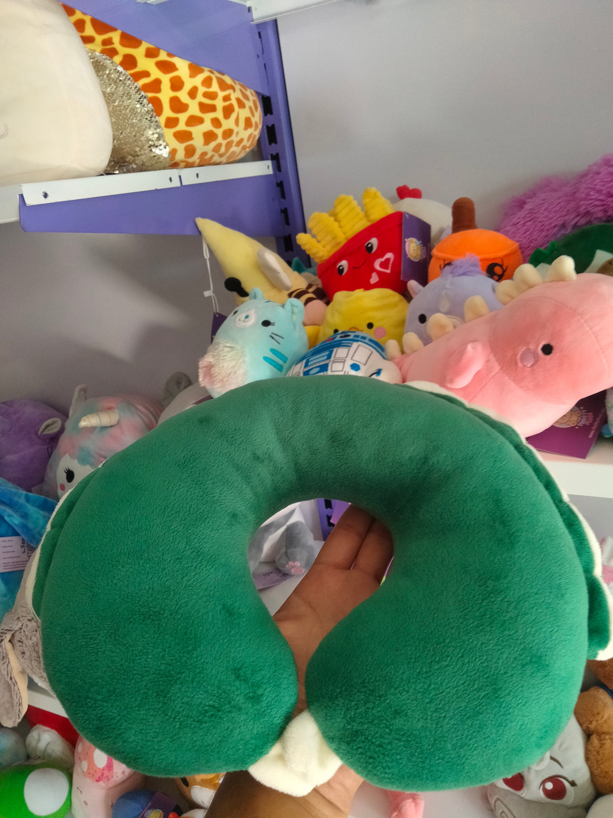 This is a green dinosaur-themed travel neck pillow from Thrifty Plush.