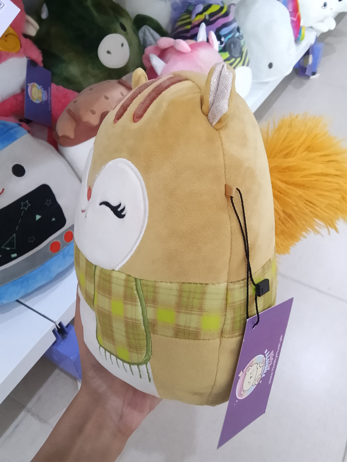Squishmallows plush toy of Erin the Squirrel wearing a plaid scarf.