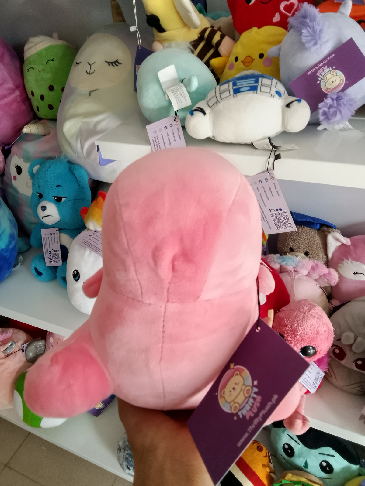 Yobush pink plush dinosaur toy holding a hear.