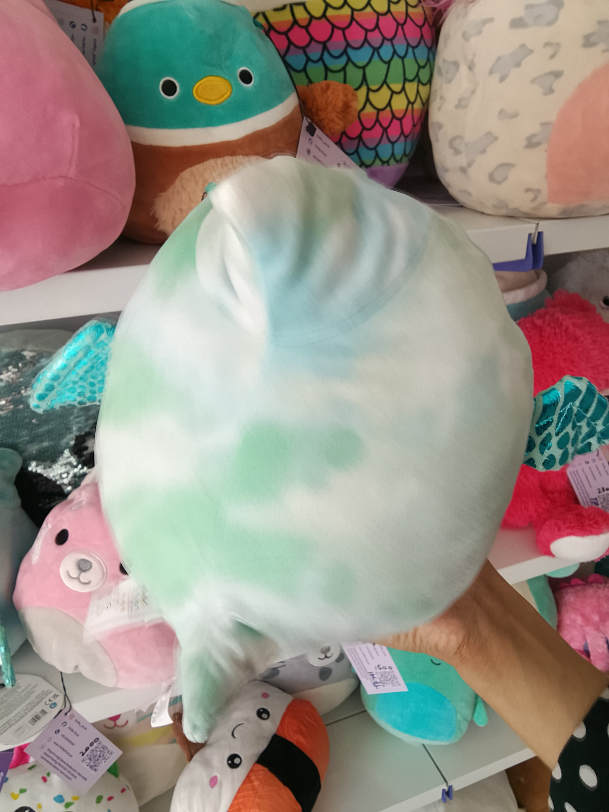 Squishmallows Shantira the Pterodactyl plush toy blue and white tie-dye design and holding a hot chocolate cup.
